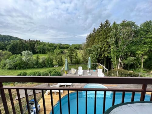 Terrasse des Gîtes Des Planchettes surplombant la piscine et la campagne verdoyante de Marigny