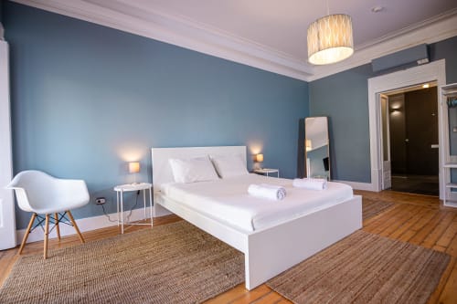 Suíte moderna do hotel VAGO Alcântara Suites em Lisboa com paredes azuis, cama branca e piso em madeira