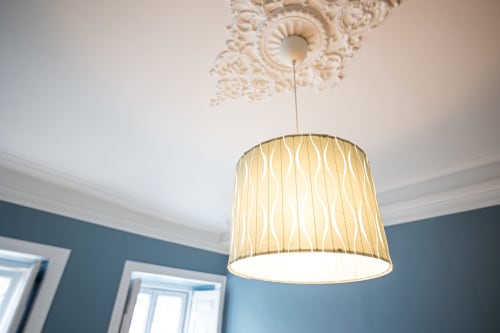 Luminária pendente elegante com cúpula creme sob rosetão ornamentado no quarto do hotel VAGO Alcântara Suites, Lisboa