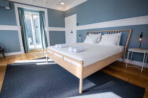 Quarto Dupla Bright Suite do VAGO Alcântara Suites, Lisboa com paredes azuis, cama de madeira, roupa de cama branca e acesso à varanda