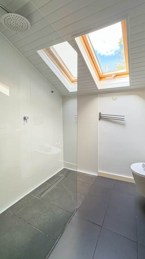 Banheiro moderno com duche walk-in, claraboias e chuveiro tipo chuva no suíte do hotel VAGO Alcântara Suites em Lisboa