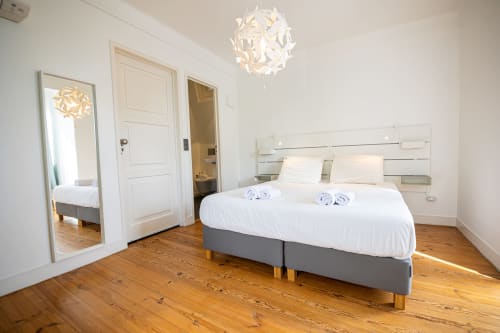 Quarto suíte moderno da VAGO Alcântara Suites, Lisboa, com cama de casal, roupa de cama branca, assoalho em madeira e design contemporâneo