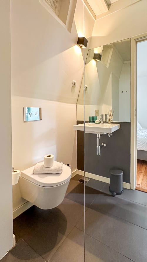 Banheiro moderno do VAGO Alcântara Suites em Lisboa com sanita suspensa, box de vidro e lavatório flutuante