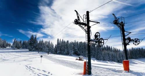 Piste enneigée avec remontées mécaniques et forêt de conifères aux Gîtes Des Planchettes à Marigny, France