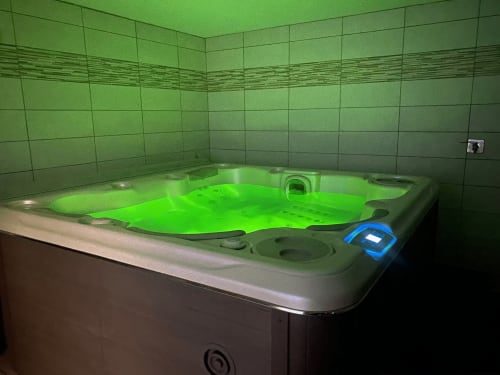 Baignoire balnéo illuminée en vert dans une salle de bains carrelée aux Gîtes Des Planchettes, Marigny