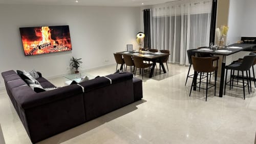 Séjour ouvert et moderne aux Gîtes Les Camélias 71 avec canapé noir, table à manger et cuisine à Oslon