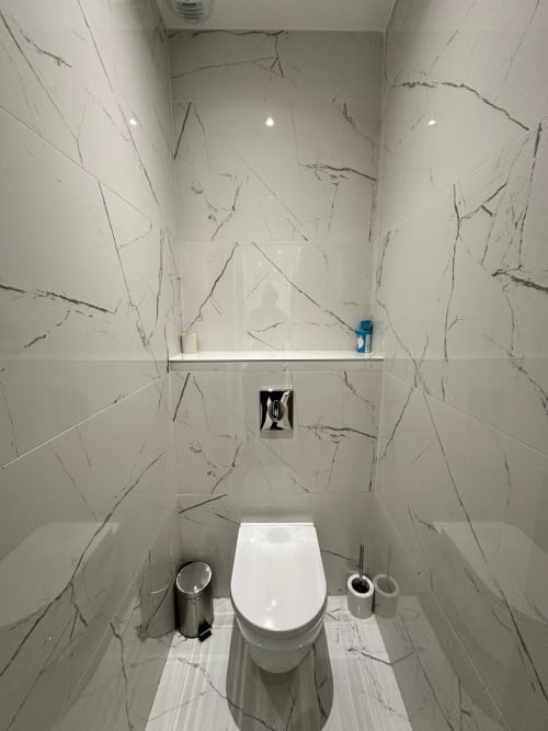 Salle de bain moderne aux carreaux gris veinés aux Gîtes Les Camelias 71 à Oslon, avec toilettes blanches et étagère