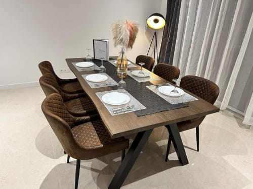 Élégante salle à manger des Gîtes Les Camelias 71 avec table en bois, chaises matelassées marron et lampadaire moderne.
