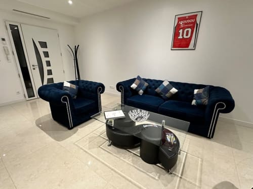 Salon moderne aux Gites Les Camelias 71 à Oslon avec canapé et fauteuil Chesterfield bleu marine, table basse en verre et