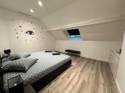 Chambre mansardée moderne aux Gites Les Camelias 71 avec lit queen-size, puits de lumière et décoration murale