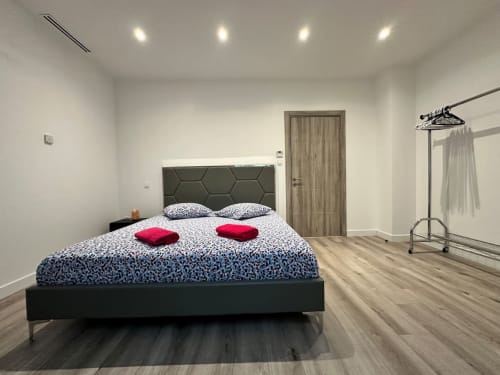 Chambre moderne du gîte Les Camelias 71 à Oslon avec lit queen-size, tête de lit hexagonale, oreillers rouges, parquet