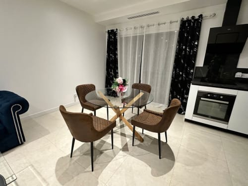 Salle à manger moderne aux Gites Les Camelias 71 à Oslon avec table ronde en verre, chaises marron et électroménager