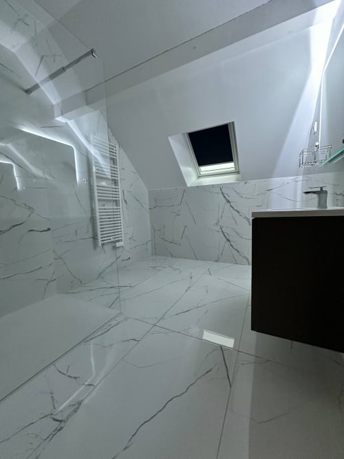 Salle de bain moderne aux Gîtes Les Camélias 71 avec carrelage marbre, douche vitrée, sèche-serviettes et puits de lumière à Oslon