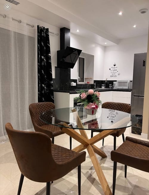 Cuisine-salle à manger moderne aux Gites Les Camelias 71 avec table ronde en verre, chaises marron et appareils contemporains