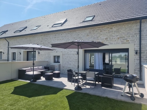Terrasse moderne du Gîtes Les Camelias 71 à Oslon, France avec salon, parasols, barbecue et pelouse entretenue