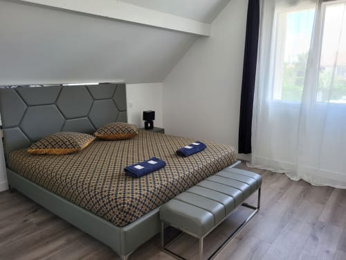 Chambre moderne aux Gîtes Les Camélias 71 à Oslon avec lit queen-size, tête de lit géométrique et baies vitrées