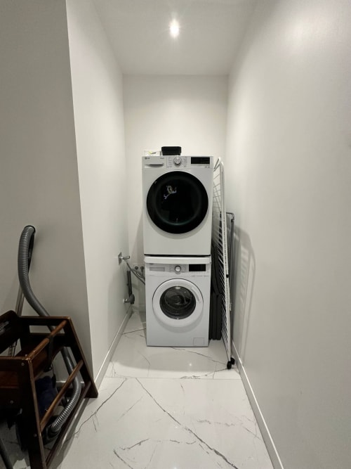Machine à laver et sèche-linge empilés dans la buanderie blanche des Gites Les Camelias 71, Oslon France