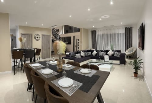 Espace ouvert de salle à manger et séjour aux Gites Les Camelias 71 à Oslon avec table noire, canapé à motifs zèbre et bar