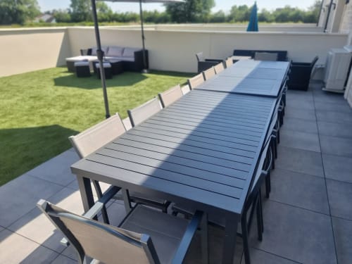 Table de salle à manger moderne avec chaises sur la terrasse des Gites Les Camelias 71 à Oslon, France, entourée de jardins luxuriants et salon