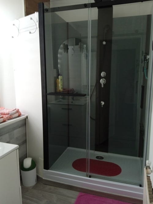 Douche moderne avec cadre noir et pomme de douche pluie dans la salle de bain de l'hôtel Les Clematies en Cotentin, Saint-Floxel