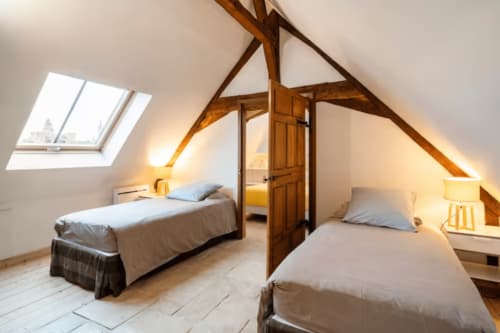 Chambre mansardée rustique à la Villa République Normandie à Caen avec poutres en bois, deux lits et lucarnes