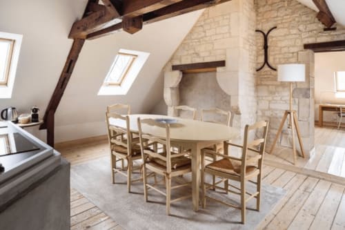 Salle à manger rustique au loft de la Villa République Normandie à Caen avec poutres apparentes, cheminée et mobilier en bois clair