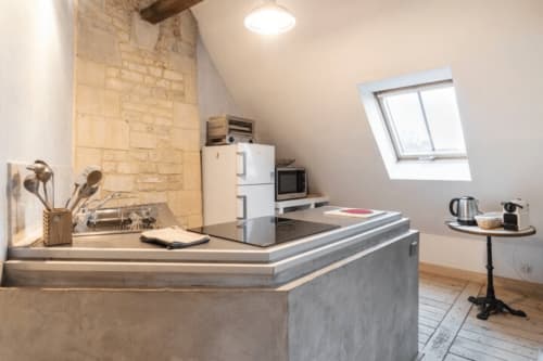 Cuisine moderne dans une chambre mansardée de la Villa République Normandie à Caen, avec plan de travail en acier inoxydable et électroménagers blancs