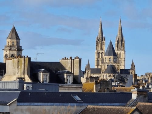 Les flèches de la cathédrale de Caen s'élèvent au-dessus des toits historiques près du gîte Villa République Normandie