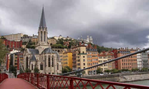 Vue du pont rouge sur l'église blanche et les bâtiments colorés de Lyon, près des Gîtes Les Camélias