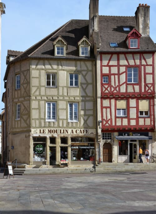 Bâtiments à colombages historiques aux façades rouges et beiges à Auxerre, avec le café Le Moulin à Café et commerces