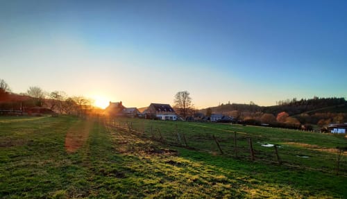 La Ferme De Werpin B&B au coucher de soleil à Hotton, Belgique, avec ses fermes rurales et pâturages verts à l'heure dorée