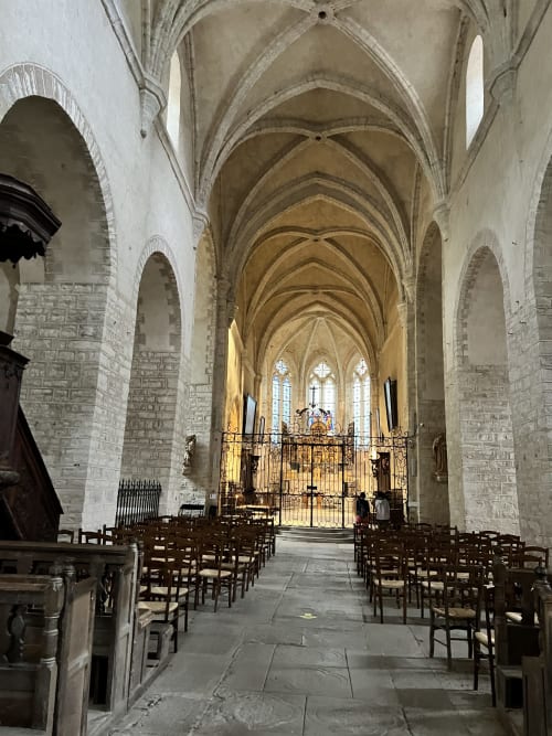 Intérieur de cathédrale gothique aux plafonds voûtés, bancs de bois et autel près de Marigny, France