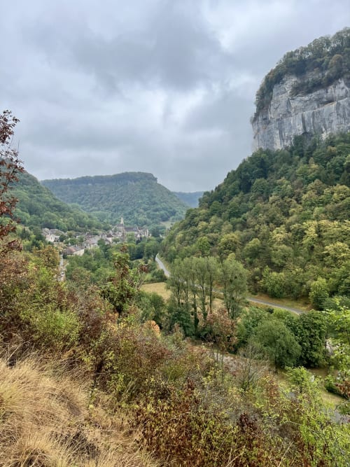Vue pittoresque de la vallée de Marigny avec rivière, falaises calcaires et église du village nichée parmi les collines boisées
