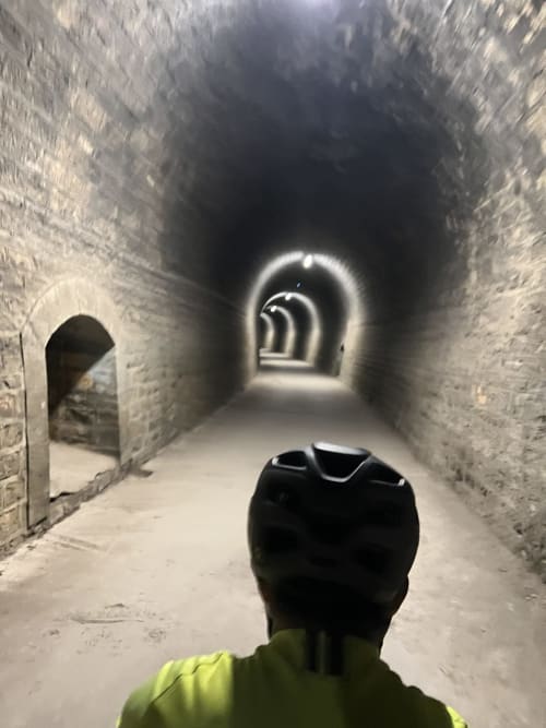 Personne en veste néon explorant un tunnel de pierre aux Gîtes Des Planchettes, Marigny