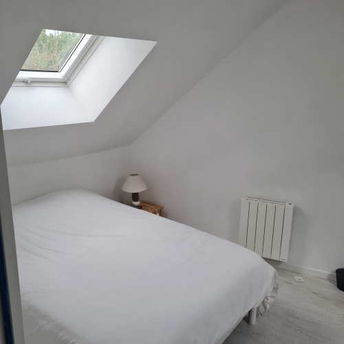Chambre lumineuse mansardée avec lucarne au Gite Les Mouettes Blessées à Le Crotoy, lit, lampe, radiateur et vue sur mer