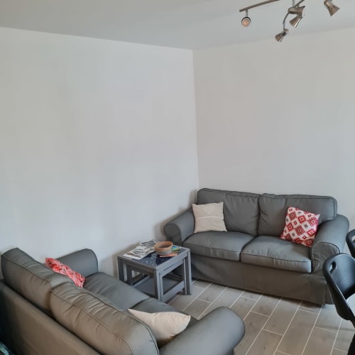 Séjour moderne du gîte Le Crotoy avec canapés gris, coussins rouges et éclairage décoratif