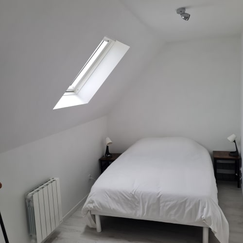 Chambre lumineuse sous les toits avec velux à la Gîte Les Mouettes Blessées au Crotoy, lit blanc et radiateur de chauffage