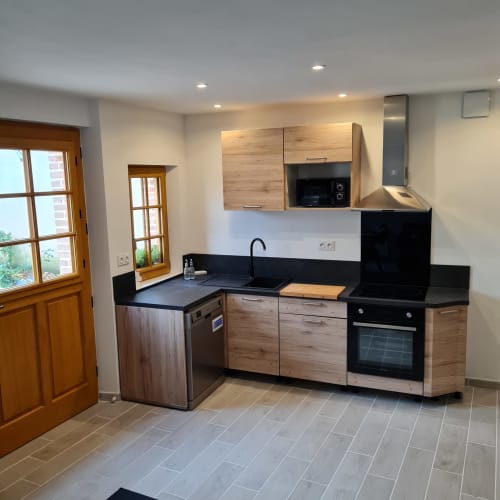 Cuisine moderne avec placards en bois et plan de travail noir au Gite Les Mouettes Blessées à Le Crotoy