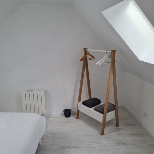 Chambre mansardée minimaliste au Gîte Les Mouettes Blessées avec portant en bois et radiateur