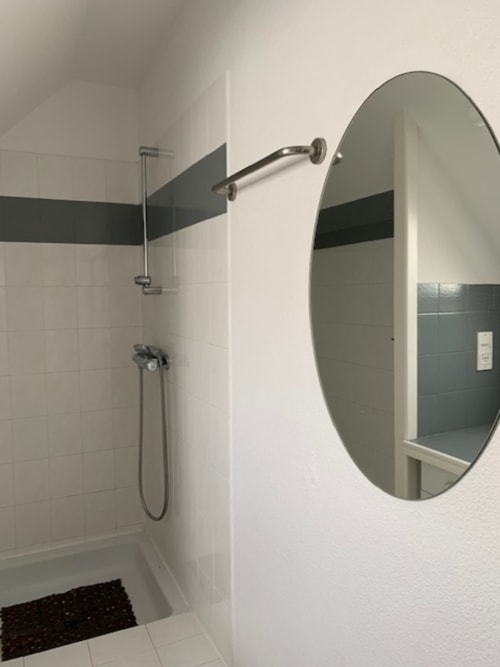 Salle de bains moderne avec miroir ovale, douche et carrelage noir dans l'appartement Belle Île