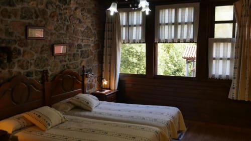 Dormitorio rústico en Hotel Rural Los Texos con dos camas, muebles de madera, papel tapiz estampado y vistas al jardín