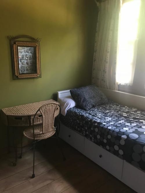 Acogedora habitación en Hotel Rural Los Texos con cama individual, silla de mimbre y vista al jardín desde la ventana