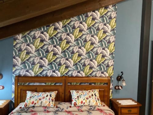 Dormitorio rústico en Hotel Rural Los Texos con cama de madera, papel tapiz floral y cojines decorativos