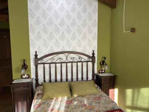 Acogedora habitación en Hotel Rural Los Texos con cama de hierro forjado, paredes verde lima y cabecero con patrón de helechos