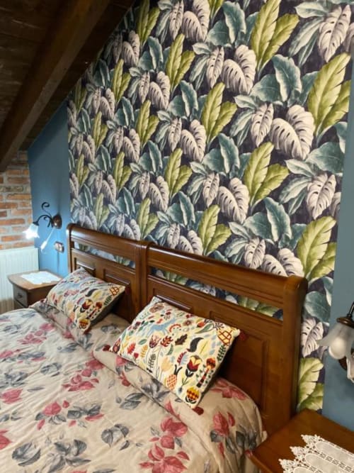 Acogedora habitación del Hotel Rural Los Texos con papel tapiz floral, cama de madera y ropa de cama estampada con vistas a los jardines.