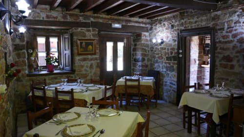 Comedor rústico de piedra en Hotel Rural Los Texos, La Riera de Covadonga, con sillas de madera y mesas iluminadas por velas
