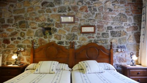 Camas gemelas en dormitorio rústico de piedra del Hotel Rural Los Texos, La Riera de Covadonga con decoración tradicional