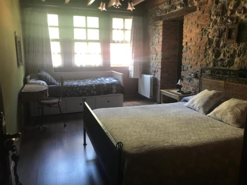 Dormitorio espacioso con dos camas en Hotel Rural Los Texos, con paredes de ladrillo visto y vistas al jardín