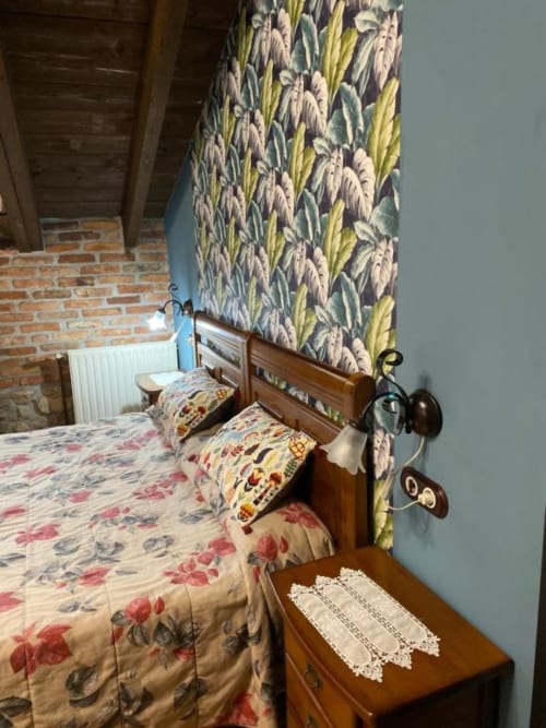 Acogedora habitación en Hotel Rural Los Texos con camas gemelas, ropa de cama floral, cortinas estampadas y techo de madera vista.