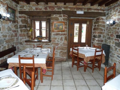 Comedor rústico de piedra en Hotel Rural Los Texos con mesas de madera, manteles blancos y decoración tradicional española